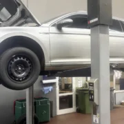 Foto zeigt silbernes Fahrzueug auf einer Hebebühne in Werkstatthalle