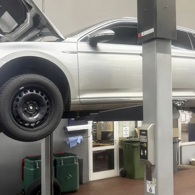 Foto zeigt silbernes Fahrzueug auf einer Hebebühne in Werkstatthalle