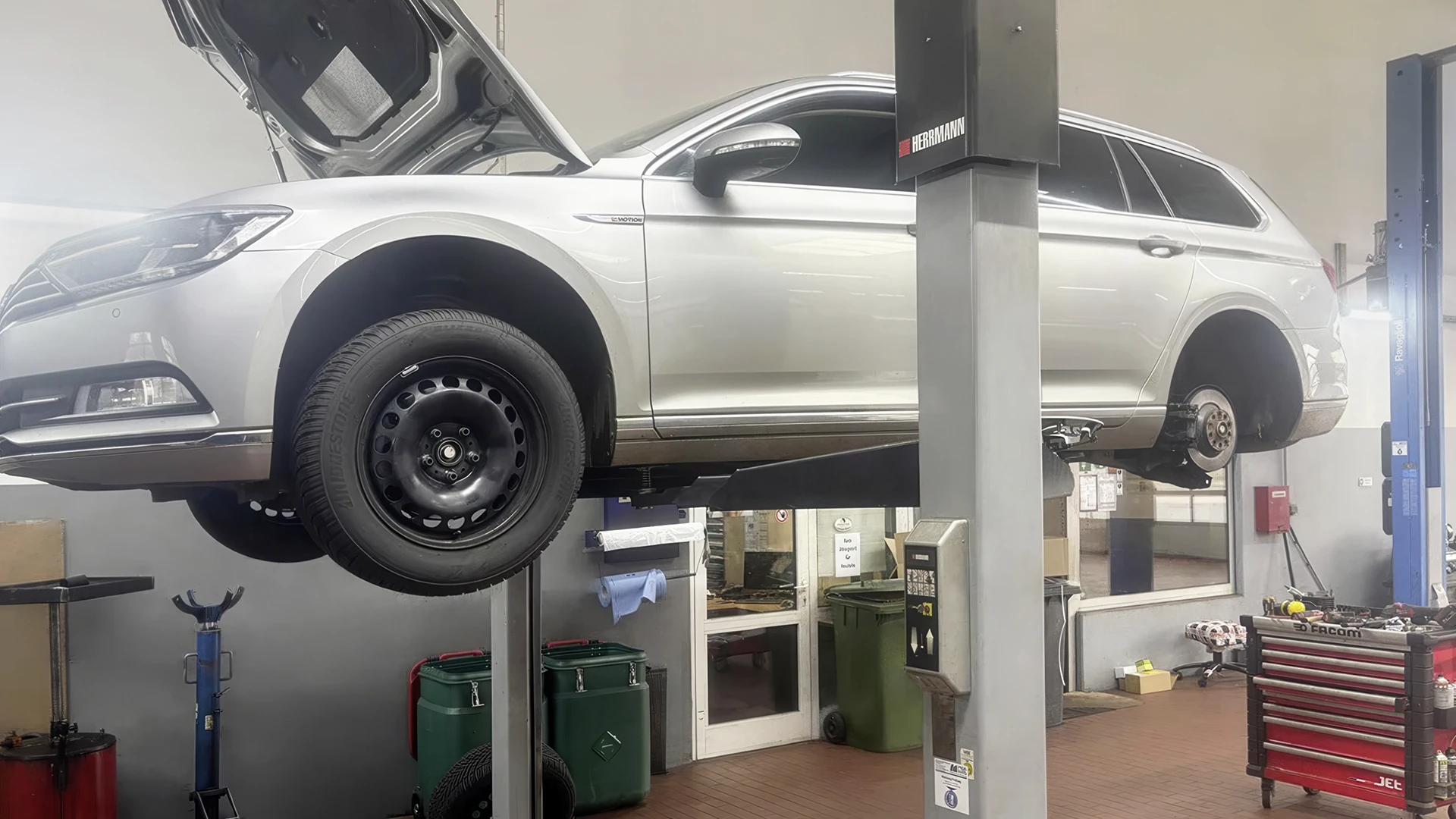 Foto zeigt silbernes Fahrzueug auf einer Hebebühne in Werkstatthalle