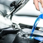 Foto blauer Scheibenfrostschutz wird im Motorraum in Behälter eingefüllt