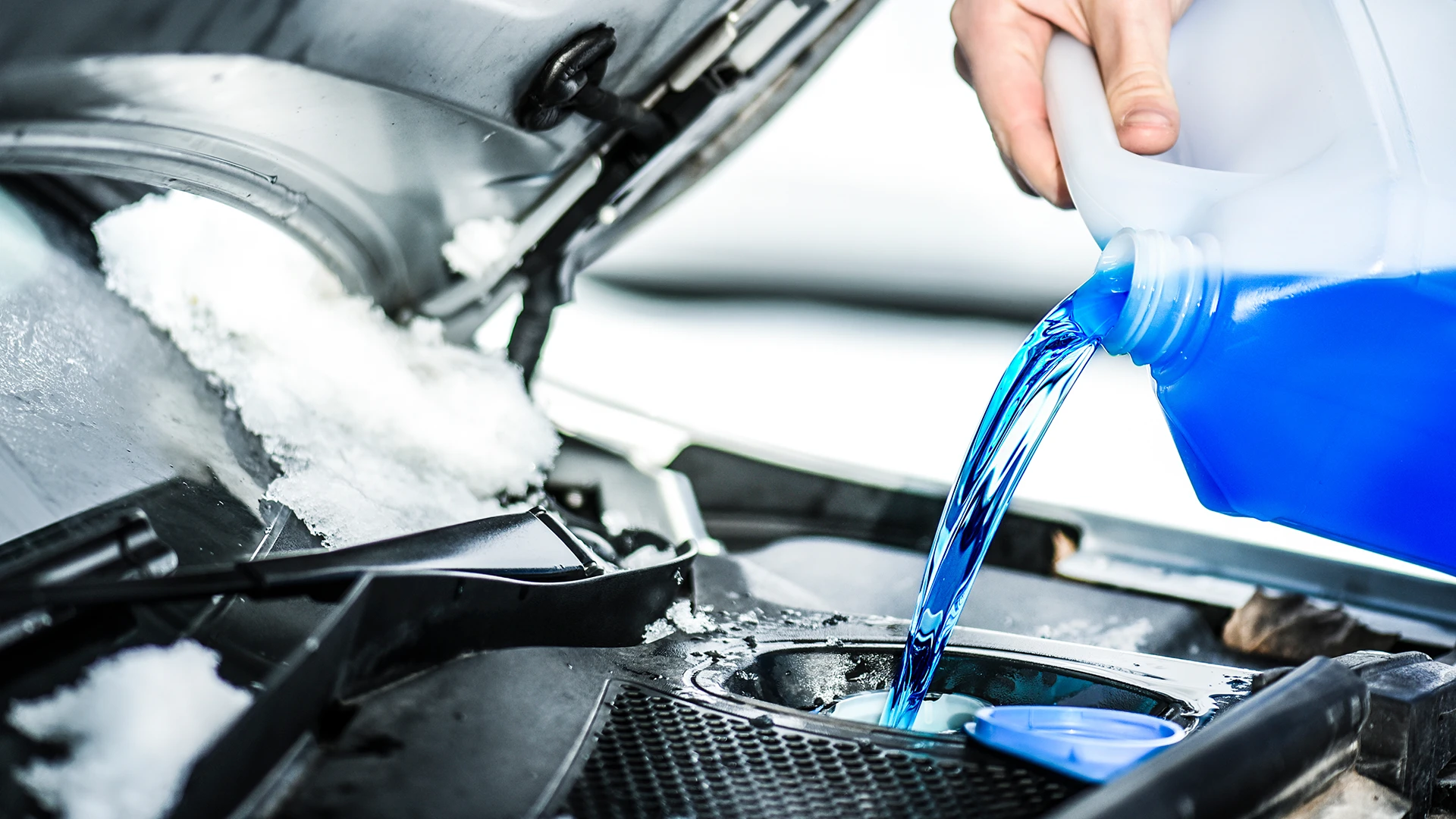 Foto blauer Scheibenfrostschutz wird im Motorraum in Behälter eingefüllt